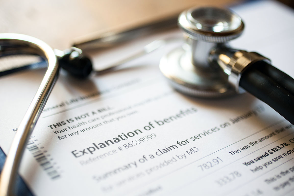 A stethoscope sits on top of a paper explanation of benefits form.| HealthDiscovery.org