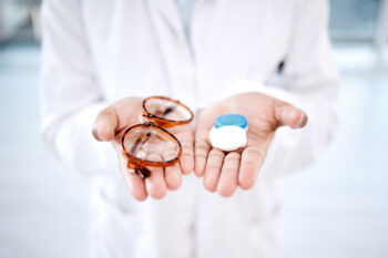 glasses and contacts in a doctor’s palms as you contemplate vision insurance | HealthDiscovery.org