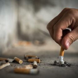 man begins tobacco cessation journey stubbing out cigarette on concrete| HealthDiscovery.org
