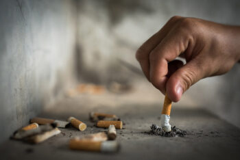 man begins tobacco cessation journey stubbing out cigarette on concrete| HealthDiscovery.org