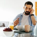 A man experiencing emotional distress picks at his breakfast with no appetite | Corporate Synergies