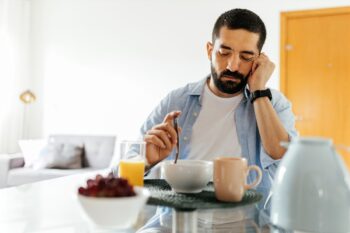 A man experiencing emotional distress picks at his breakfast with no appetite | Corporate Synergies