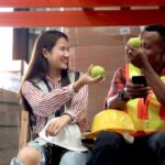 Asian female giving apple to African-American male co-worker in warehouse for heart health | Corporate Synergies