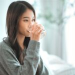 Asian woman drinking water in morning for healthful habits | Corporate Synergies