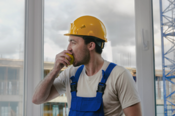 Construction worker having a break and eating apple | Corporate Synergies