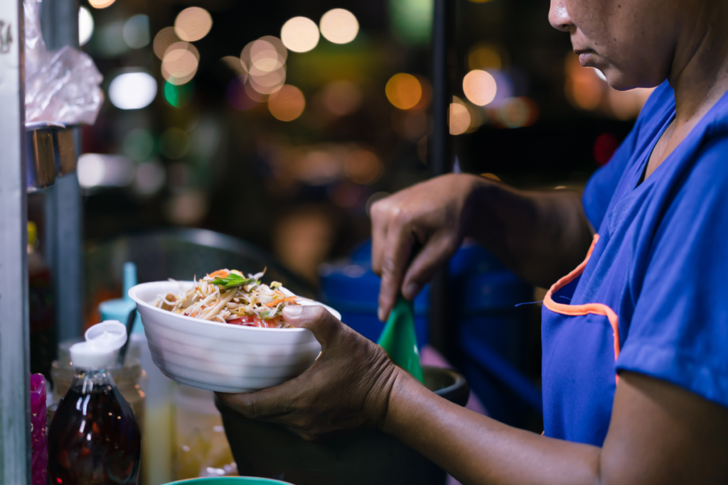 Night worker buying green papaya salad at night from street vendor | Corporate Synergies