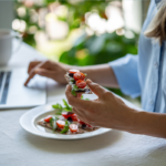 Woman eats nutritious snack while using laptop to prevent work burnout | Corporate Synergies