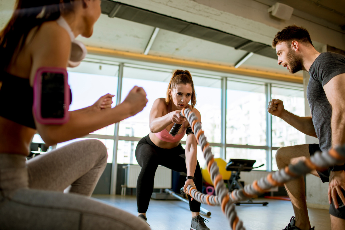 Women doing rope workout at gym with trainer as a common fitness insurance benefit | Corporate Synergies