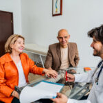 Doctor talking to older couple in office helping them understand Medicare | Corporate Synergies