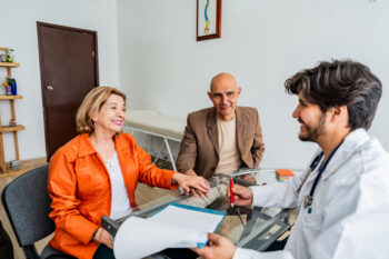 Doctor talking to older couple in office helping them understand Medicare | Corporate Synergies