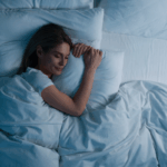 Woman enjoying sleep wellness benefits by sleeping in bed at night | Corporate Synergies