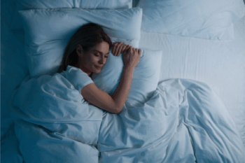 Woman enjoying sleep wellness benefits by sleeping in bed at night | Corporate Synergies