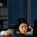 Sleepy worker with coffee demonstrating how sleep and work performance are connected | Corporate Synergies