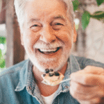 Senior man enjoying a dessert of blueberries for brain health | Corporate Synergies