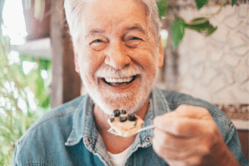 Senior man enjoying a dessert of blueberries for brain health | Corporate Synergies