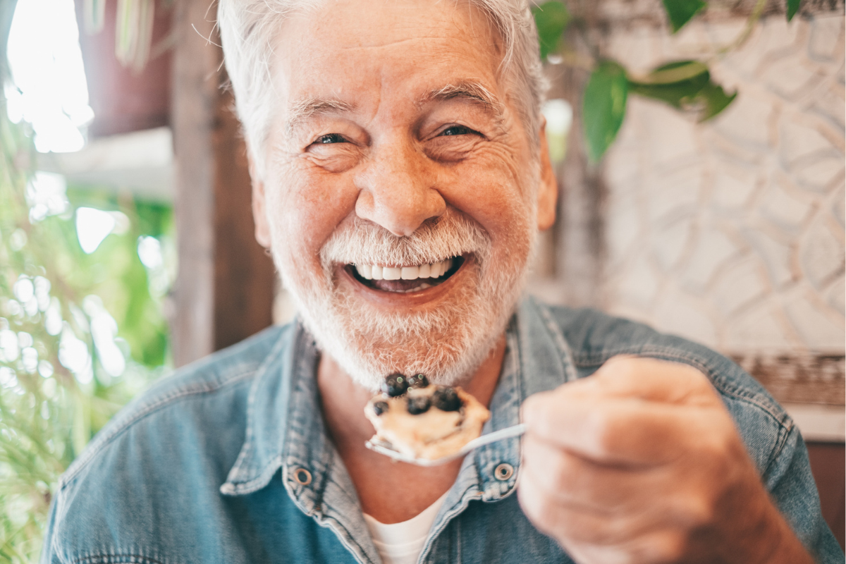 Senior man enjoying a dessert of blueberries for brain health | Corporate Synergies