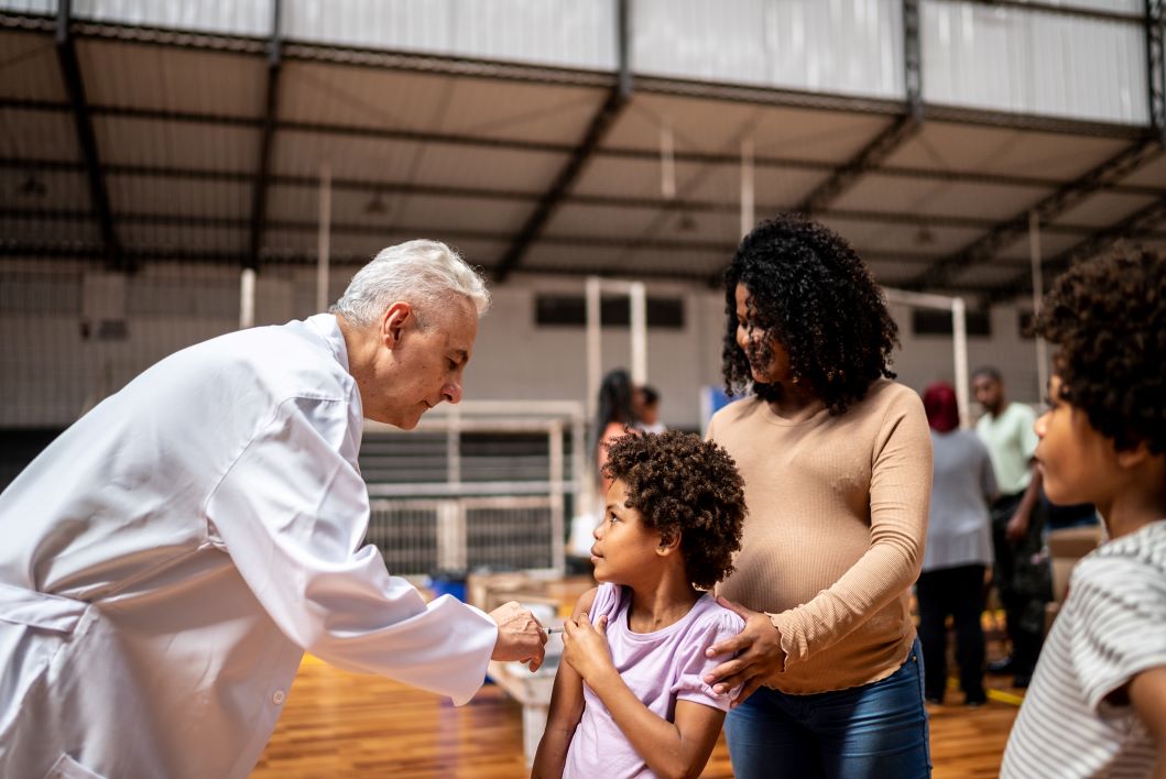 Insurance-covered preventive services allow a doctor to vaccinate a low-income family at community center | Corporate Synergies