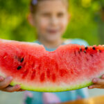 Child holding a bitten slice for watermelon superfood benefits and food high in lycopene | Corporate Synergies