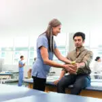 therapist teaches young man hand weight exercises for physical and occupational health | Corporate Synergies