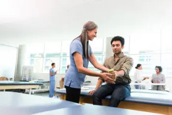 therapist teaches young man hand weight exercises for physical and occupational health | Corporate Synergies
