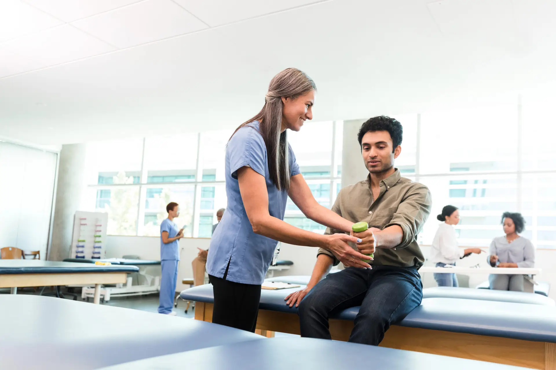therapist teaches young man hand weight exercises for physical and occupational health | Corporate Synergies